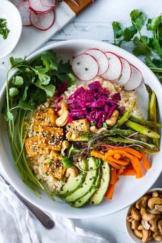 a bowl filled with rice, vegetables and cashews on top of a table