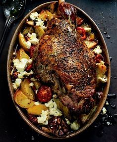 a roasting pan filled with potatoes, meat and other food on top of a table