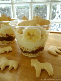 an animal cracker parfait in a plastic cup on top of a wooden table