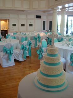 a room filled with lots of tables covered in white and blue cloths