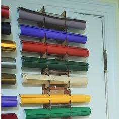 several rolls of colored paper are hanging on a white wall next to a door that has a bunch of different colors in it