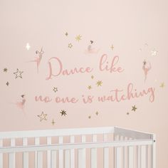 a baby's room with pink walls and gold stars on the wall, there is a white crib in front of it