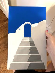 a person holding up a blue and white poster with stairs leading to an arch in the sky