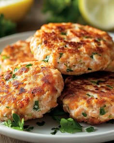 four crab cakes on a plate with parsley and lemon wedges in the background