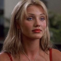 a woman wearing a red tank top with a necklace on it's neck and looking off to the side