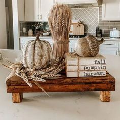 a wooden bench topped with books and pumpkins on top of a kitchen counter next to an oven