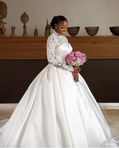 a woman in a white wedding dress holding a bouquet of flowers and posing for the camera