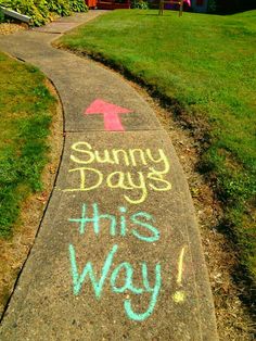 a sidewalk with chalk writing on it that says sunny days this way and an arrow