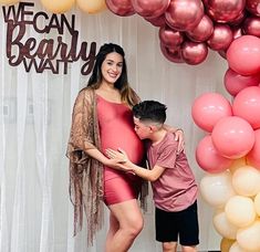 a woman and boy standing next to each other in front of balloons