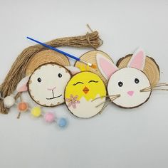 three wooden cut outs with some bunny and chick faces on them, one is holding a knitting needle