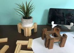 some wooden blocks are sitting on a desk next to a potted plant and computer monitor