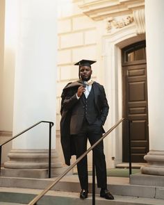 a man in a graduation cap and gown standing on steps