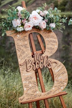 a wooden sign with flowers and greenery on it