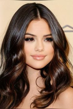 a woman with long dark hair and brown eyeshadow is posing for the camera