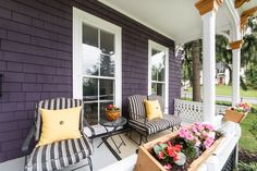 the front porch is decorated with striped furniture and flowers