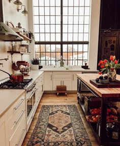 a kitchen filled with white cabinets and lots of counter space next to a large window