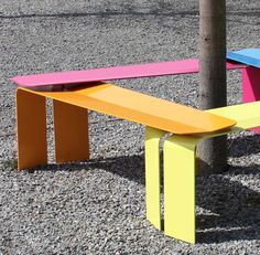 two colorful benches sitting next to each other on top of a gravel covered park ground