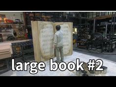 a man standing next to a large book in a room filled with shelves and boxes