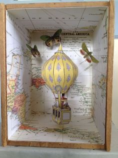 an open box with a yellow and white hot air balloon in the middle on top of a map