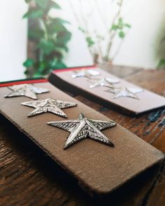 some silver stars are sitting on top of a brown piece of cloth with red trim