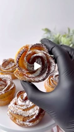 a person in black gloves is holding up some pastries on a white platter