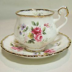 an antique tea cup and saucer with gold trimmings on the rim, decorated with pink flowers