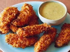 some fried food is on a blue plate with a bowl of sauce in the background