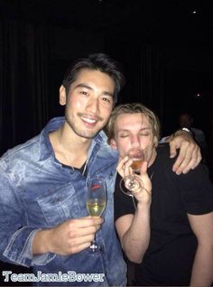 two men drinking wine and smiling at the camera