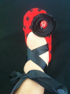 a ladybug shoe with a black ribbon around it and a flower on top