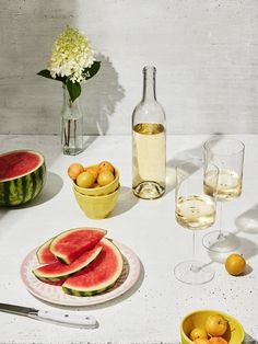 watermelon slices, oranges and other fruit on a table with wine glasses