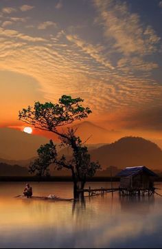 the sun is setting over a lake with a boat in it