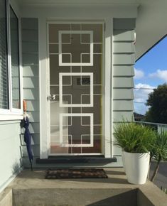 the front door of a house with a potted plant on the step and an entry mat