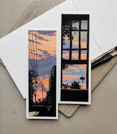 two cards with an image of a city at sunset and a pen on the table