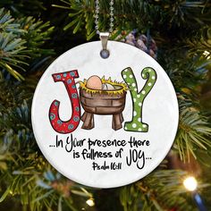 a christmas ornament hanging from a tree with the word joy on it and an egg in a basket