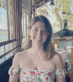 a woman sitting at a table smiling for the camera