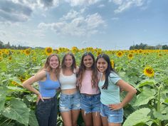 four girls standing in front of a sunflower field