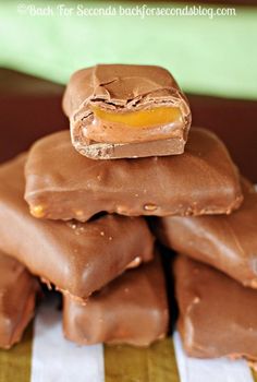 a stack of chocolate covered candy bars on top of a striped table cloth with a green and white napkin