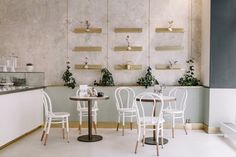 a restaurant with white chairs and tables in front of a wall mounted planter filled with potted plants