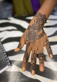 a woman's hand with hennap and flowers painted on the top of it