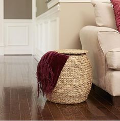 a white couch sitting next to a wooden floor in front of a red throw pillow