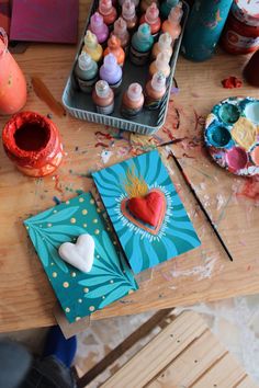 the table is covered with art supplies and crafting supplies, such as paints, paper hearts