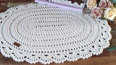 a crocheted doily is sitting on a table next to flowers and a book