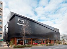 a mazda dealership on the corner of a street in front of a tall building