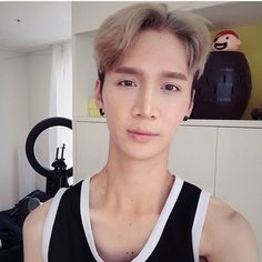 a young man is taking a selfie in the mirror while wearing a black and white tank top