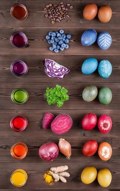 an array of different fruits and vegetables are arranged on a wooden surface, including eggs, onions, broccoli, blueberries, celery, radishes