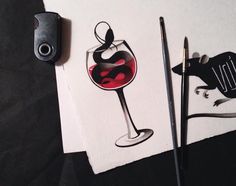 three different types of wine on paper next to ink pens and marker pen, one with a glass of red wine in it