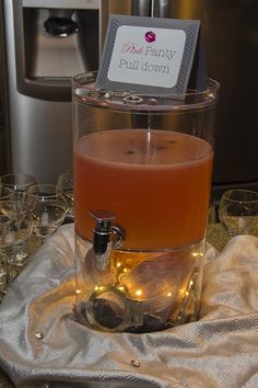 a drink dispenser sitting on top of a table filled with glasses and bottles