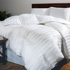 a bed with white comforter and pillows on top of it