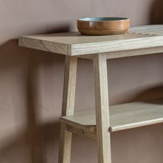 a bowl sitting on top of a wooden table next to a shelf in a room