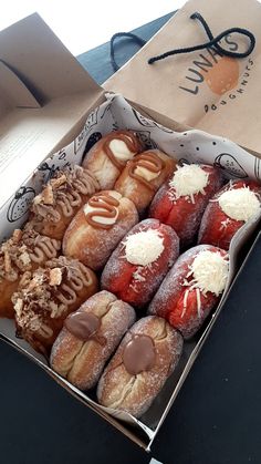 a box filled with lots of different types of donuts on top of a table